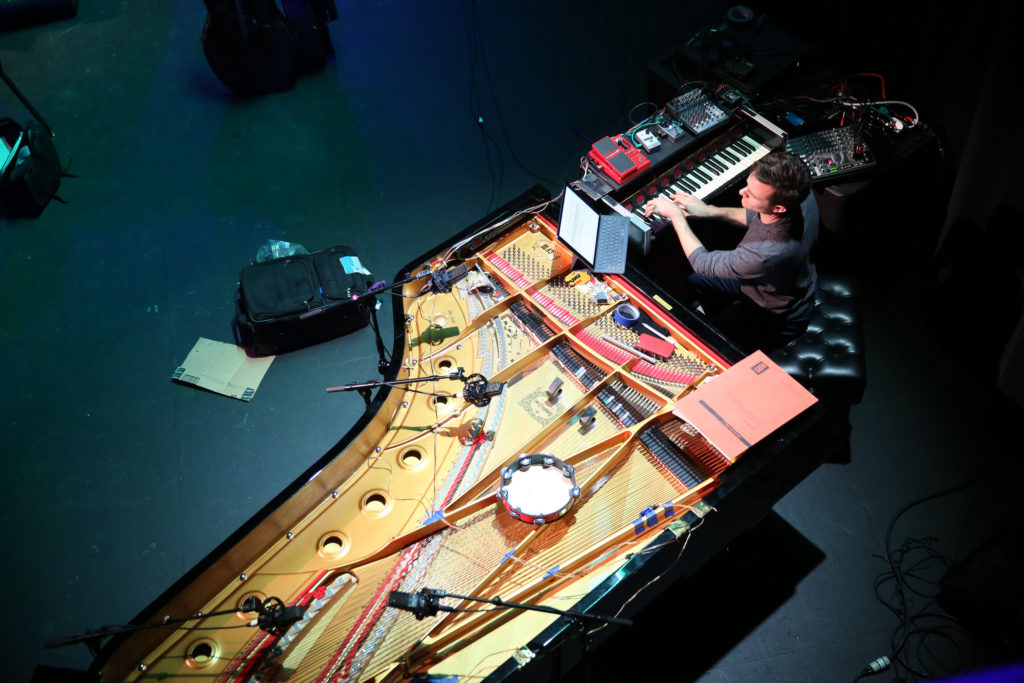 Overhead shot of a pianist playing on digital keyboard perpendiculat to grand piano