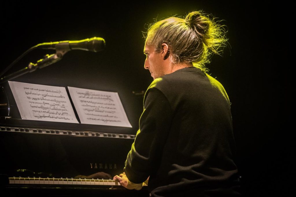 Photo of male pianist with hair in bun mid-performance concentration